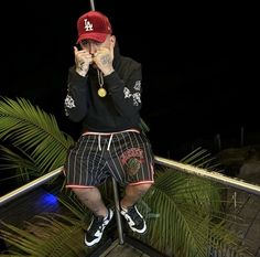 a man sitting on top of a metal railing holding a baseball bat over his face