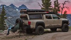 a truck with a hammock strapped to it's back parked on a dirt road