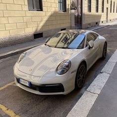 a white sports car parked on the side of the road in front of a building