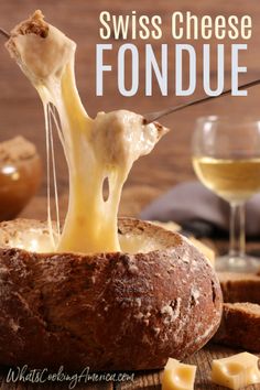 cheese fondue being scooped into bread bowl with wine glasses in the background and text overlay reading swiss cheese fondue