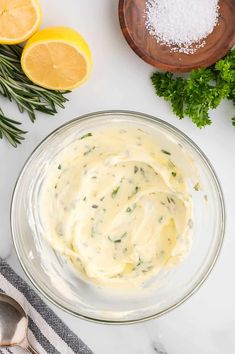 a bowl filled with sauce next to sliced lemons and parsley