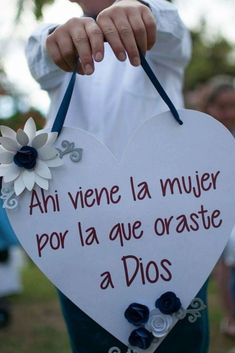 a person holding a heart shaped sign with flowers on it