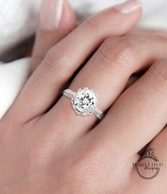 a woman's hand with a white diamond ring on her left hand and the other hand holding an engagement ring