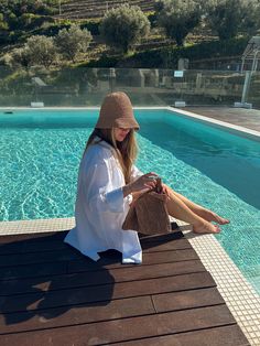 a woman sitting on the edge of a swimming pool