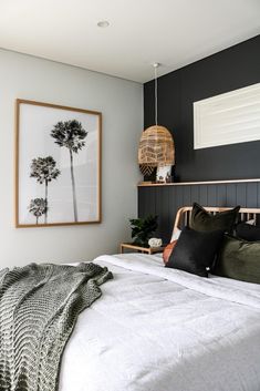 black and white bedroom with palm trees on the wall, bed linens and pillows