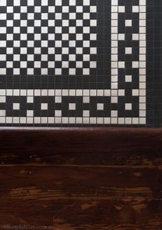 a wooden bench sitting in front of a tiled wall