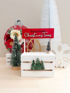 christmas trees are on display in front of a sign and other holiday decorations with snowflakes