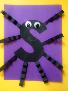 the letter s made out of construction paper with eyes and legs on it, sitting in front of a purple background