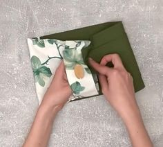 a person is wrapping a napkin on top of a green folder with leaves and pineapples