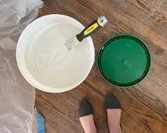 two women standing in front of a plastic container with a spatula on the floor