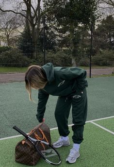 a woman bending over to pick up a tennis racquet