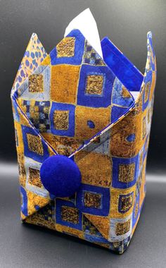 an origami box with blue and yellow squares on the inside, holding a tissue paper