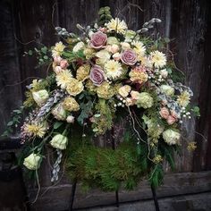 a bouquet of flowers sitting on top of a wooden table next to a fence covered in greenery