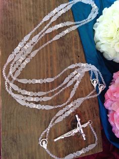 a rosary and flowers on a wooden table