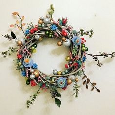 a wreath made out of branches and ornaments hanging on the wall next to a white wall