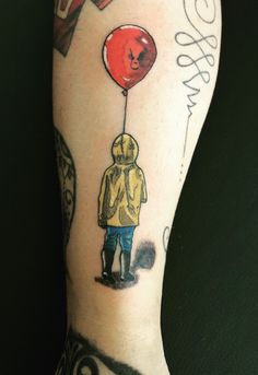 a person with a tattoo on their arm holding a red balloon that says love is in the air