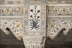 an intricately decorated wall with flowers and leaves on it's sides, painted in white