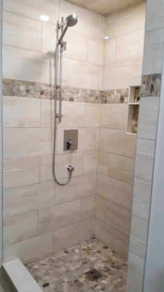 a walk in shower sitting next to a tiled wall