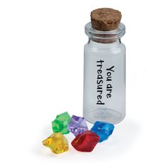 a glass bottle filled with different colored dices next to a cork top jar that says trust yourself