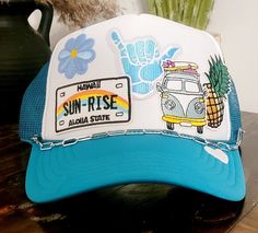 Turquoise and white custom beachy trucker hat. Multiple beach theme patches with silver chain detail. Mesh back hat with adjustable snap band. Fun Blue Trucker Hat For Vacation, Blue Adjustable Summer Trucker Hat, Blue Adjustable Trucker Hat For Summer, Blue Fun Hat For Beach Season, Fun Blue Hats For Beach Season, Fun Blue Hat For Beach Season, Blue Snapback Trucker Hat For Festival, White Trucker Hat For The Beach, Blue Trucker Cap For Festivals