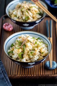 two bowls filled with rice and vegetables next to chopsticks