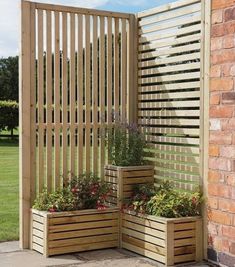 three wooden planters sitting in front of a brick wall next to a green field