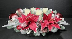 a centerpiece with candles, poinsettis and other holiday decorations on a black background