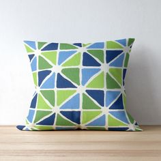 a blue and green pillow sitting on top of a wooden table