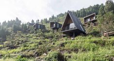 the house is built on top of a hill with grass and trees in front of it