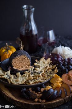 an assortment of cheeses, crackers and fruit on a plate