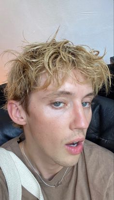 a young man with blonde hair sitting on a couch