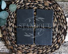 four square slate coasters sitting on top of a woven wicker basket with leaves