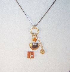 "A silver 17\" gold necklace with a pendant of various charms, crystals and gemstones. This pendant features a beautiful topaz Swarovski crystal bicone, a shining copper Stairway Swarovski crystal, a gold filigree bead, a small pearl heart, and a small gold heart all on a gold filled ring. Necklace has a gold chain with lobster claw clasp. Can be shortened or an extension can be added - please send message to seller when ordering if a length change is required." Gold Dangle Crystal Necklaces, Gold Crystal Charm Necklaces, Gold Crystal Lariat Necklace, Gift Lariat Charm Necklaces, Copper Heart Pendant For Jewelry Making, Unique Gold Crystal Jewelry, Gold Copper Pendant Crystal Necklace, Gold Copper Jewelry For Anniversary, Gold Sterling Silver Lariat Necklace With Dangle