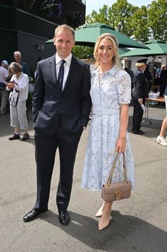 a man and woman standing next to each other in front of an outdoor area with umbrellas