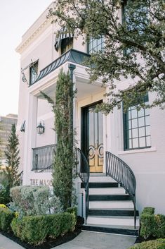 a white building with stairs leading up to the front door and steps down to the second floor