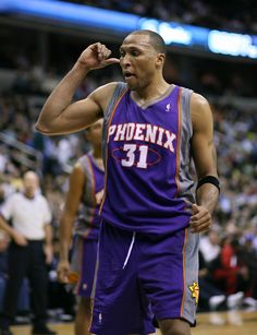 a man in a purple jersey is standing on the court with his fist raised up