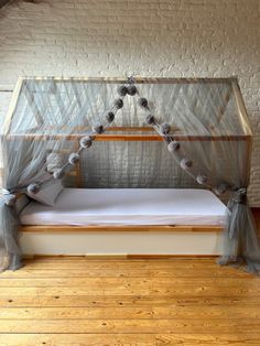 a bed that is sitting on top of a hard wood floor next to a brick wall