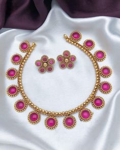 This traditional gold-plated necklace set, adorned with vibrant red and green stones, is a beautiful example of classic Indian temple jewelry. The intricate design, inspired by traditional craftsmanship, features round stones framed with gold detailing. The matching earrings complete the set, offering a cohesive and elegant look. Perfect for brides, weddings, or festive occasions, this necklace set adds a touch of elegance and sophistication to any outfit. Whether paired with traditional attire or modern outfits, this jewelry set is versatile and timeless, making it a must-have for any jewelry collection. Features: Gold-plated necklace with red and green stones Traditional Indian temple jewelry design Matching earrings included for a complete look Ideal for bridal wear, weddings, and festi American Diamond Necklaces, Temple Jewelry, Oxidized Necklace, Indian Temple, Bangle Ring, Green Stones, Traditional Attire, Jhumka Earrings, Temple Jewellery