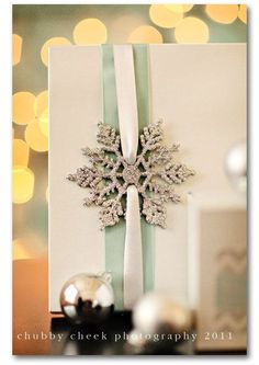 a christmas card with a snowflake on the front and green ribbon around it