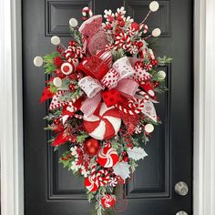 a christmas wreath hanging on the front door decorated with candy canes and candies