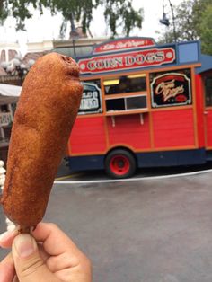 a person holding up a hot dog in front of a food truck