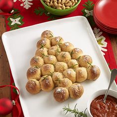 a white plate topped with rolls covered in powdered sugar and tomato sauce next to a bowl of dipping sauce