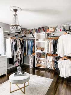 an organized closet with clothes hanging on shelves and a chandelier in the corner