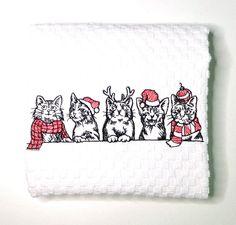 a white towel with four cats wearing christmas hats and scarfs on top of it