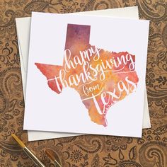 a card with the words happy thanksgiving from texas written in watercolor on it next to a pen