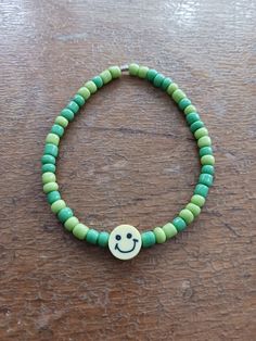 A green seed bead bracelet with a yellow smiley face centerpiece bead for any occasion. Green Aesthetic Smiley Face, Green Fun Friendship Bracelets With Colorful Beads, Fun Green Friendship Bracelets With Colorful Beads, Fun Green Friendship Bracelet With Colorful Beads, Green Fun Jewelry With Letter Beads, Trendy Green Friendship Bracelets With Colorful Beads, Casual Yellow Beaded Bracelets With Smiley Face, Fun Green Jewelry With Letter Beads, Green Beaded Friendship Bracelets