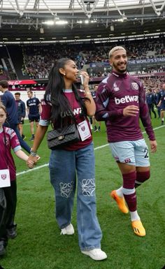 a man and woman walking across a soccer field