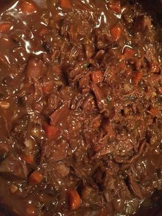 beef and carrots are cooked in a pot on the stove top, ready to be eaten