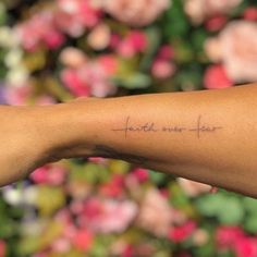 a woman's arm with the word tattoo on it and flowers in the background