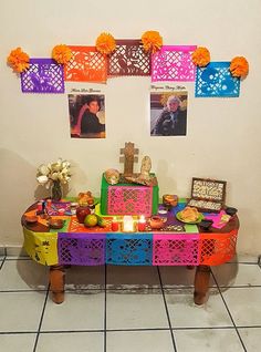 a colorful table with pictures on the wall behind it and candles in front of them